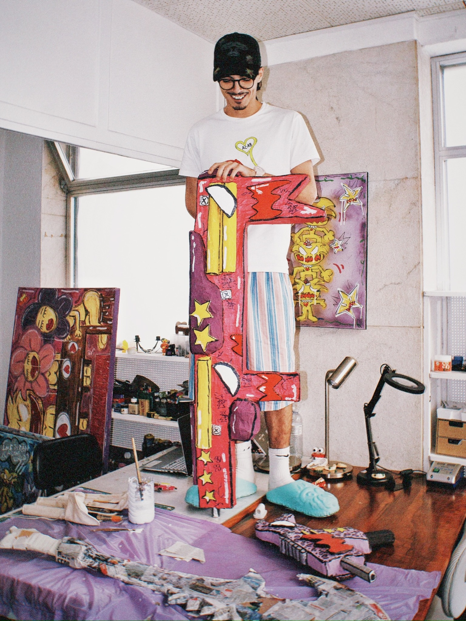 Tomás no atelier, de pé, com uma peça pintada quase da sua altura