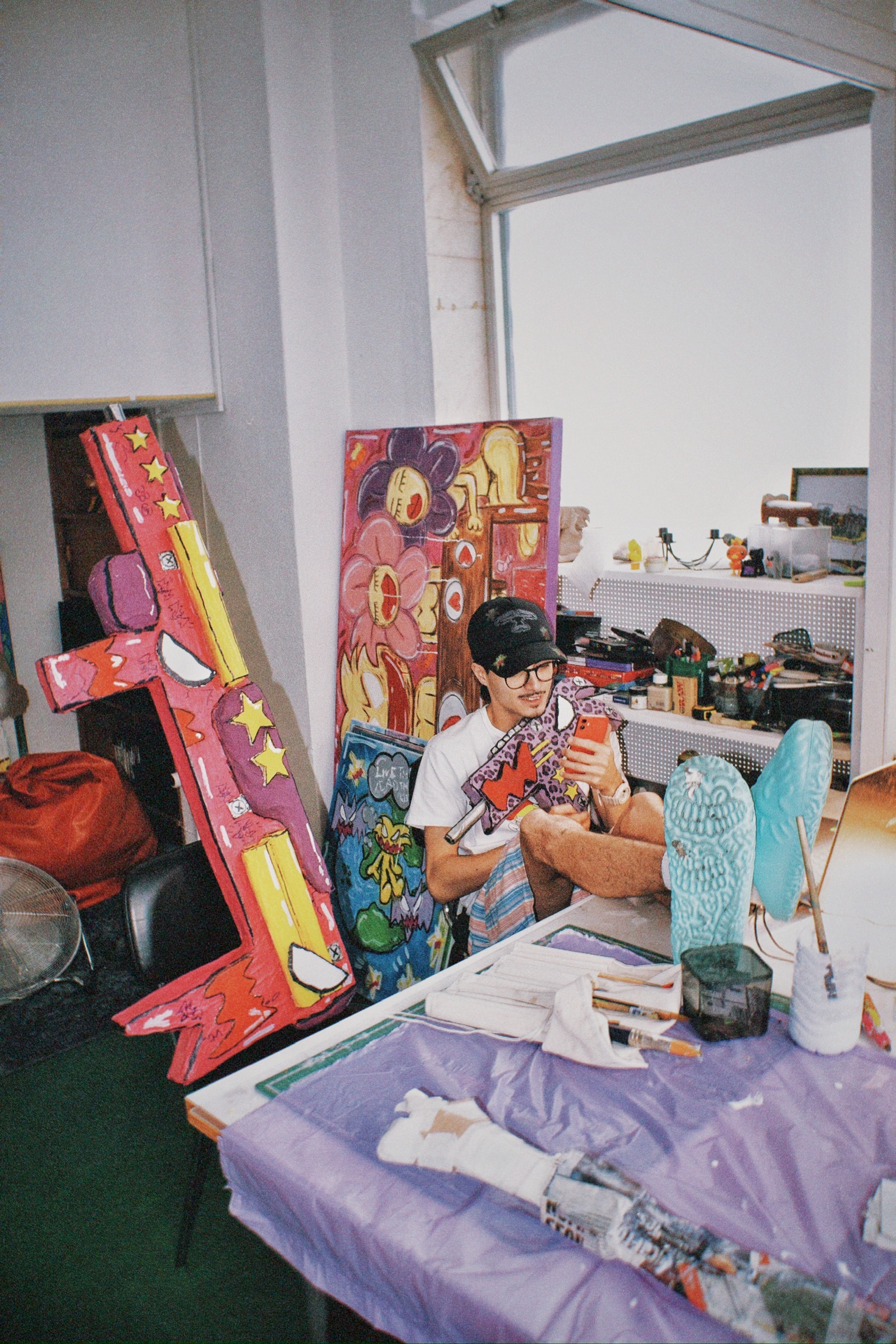 Tomás no atelier a pintar, com as peças recortadas encostadas à parede